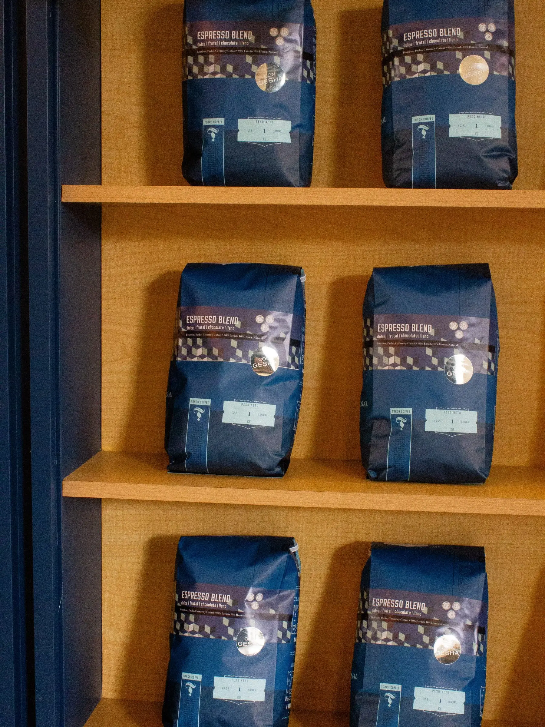 Estante de madera con bolsas azules de café Torch para llevar