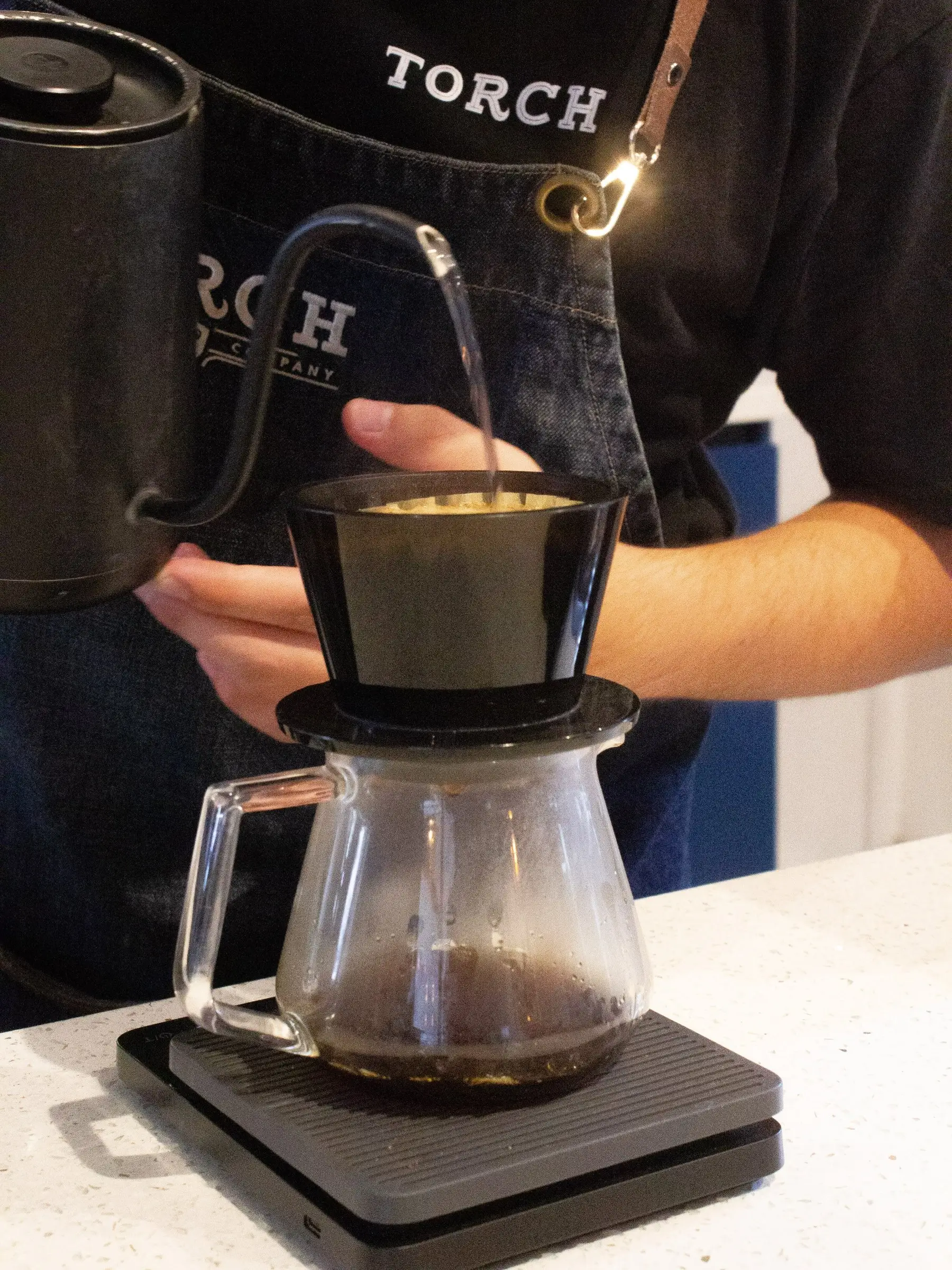 Barista de Torch sirviendo agua caliente en un filtro sobre una balanza digital