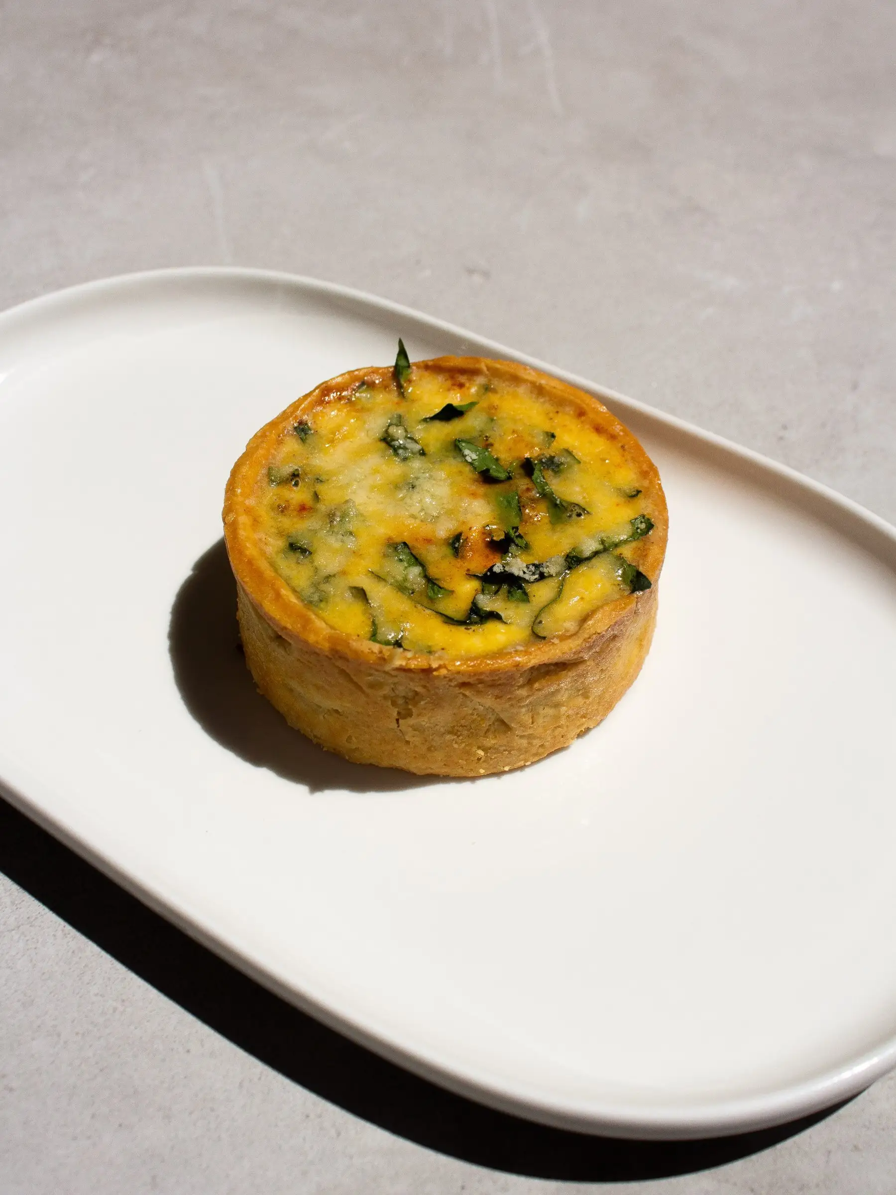 Quiche Florentine de espinaca y quesos en un plato blanco