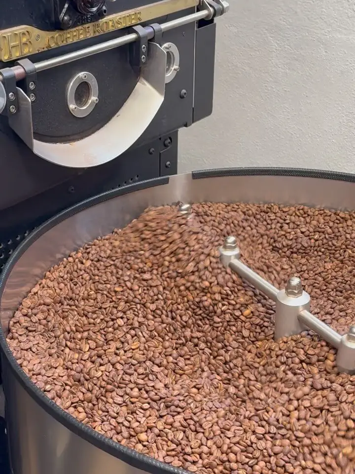 Granos de café girando en el tambor de enfriamiento de un tostador